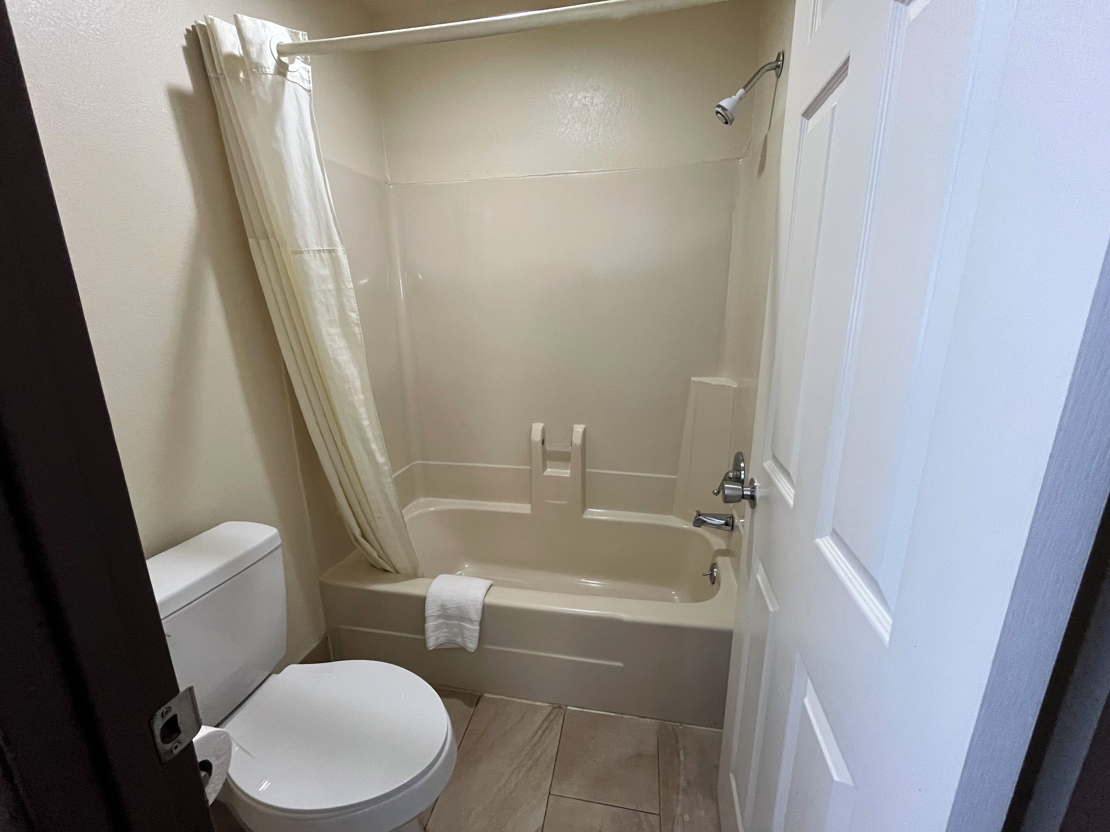 A small bathroom with a toilet, a bathtub, and a shower.