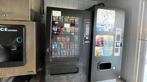 A vending machine with a variety of snacks and drinks, a push button, and a payment interface. - Budget Inn (Nassawadox)