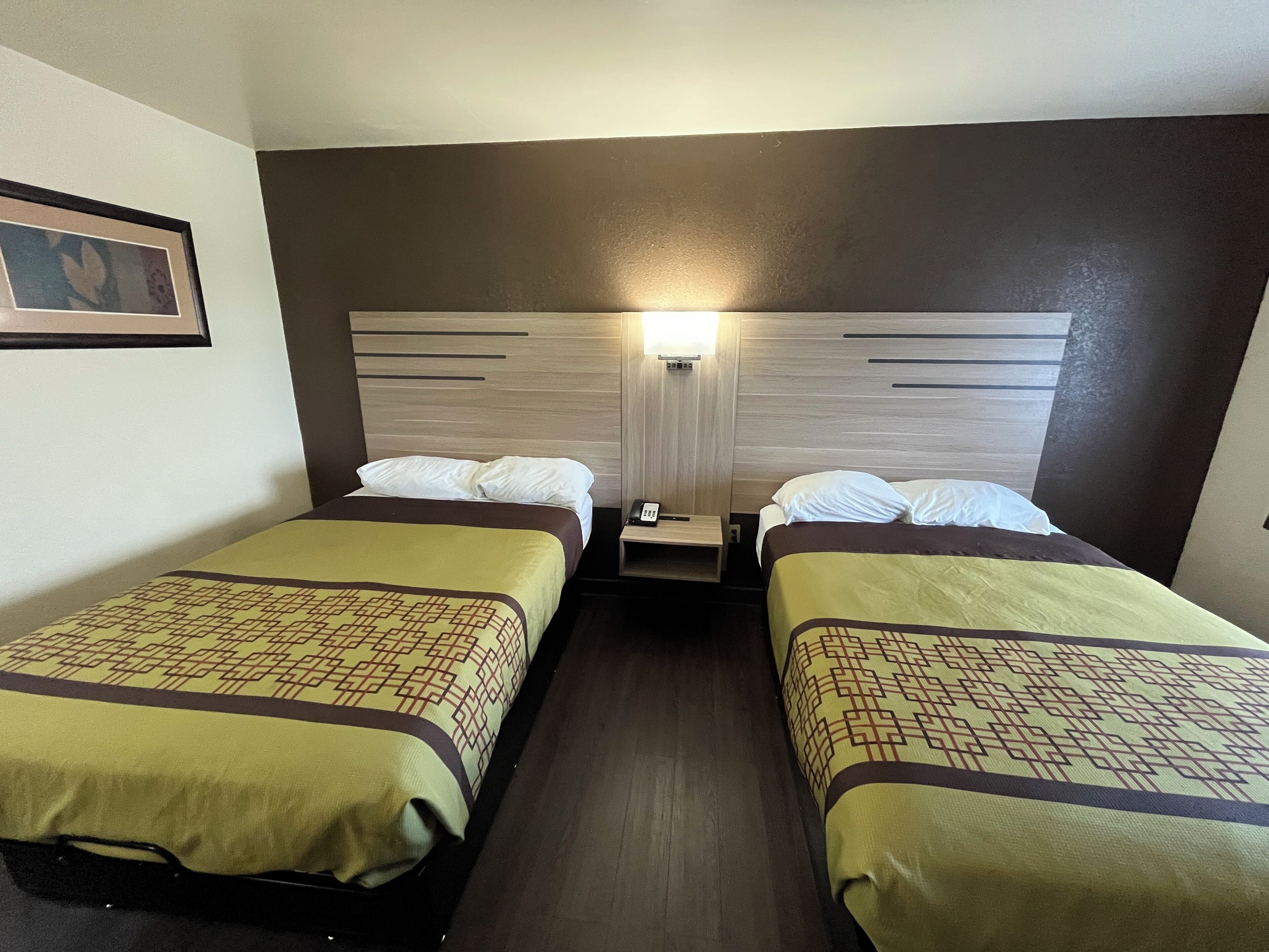 Une chambre d’hôtel avec deux lits simples, chacun agrémenté d’une couvre-lit à motifs et d’une table de chevet avec une lampe.