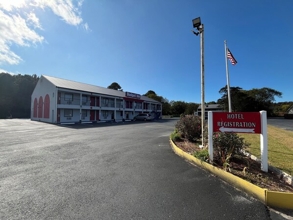 A motel with a registration sign, a flagpole, and a parking lot.