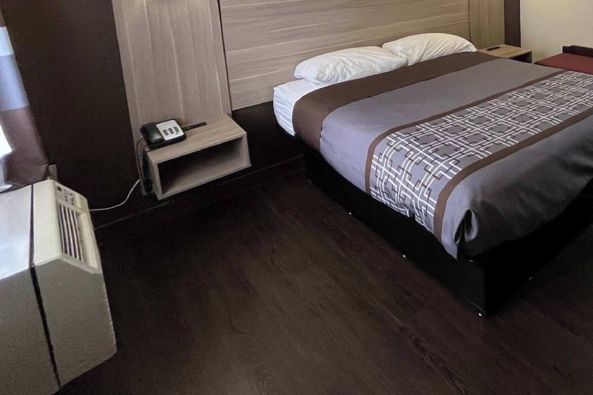 A hotel room with a bed, bedside tables, a lamp, and a phone.