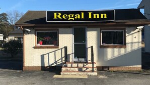 Un edificio pequeño con un letrero que dice "Regal Inn" y unas escaleras que conducen a la entrada.