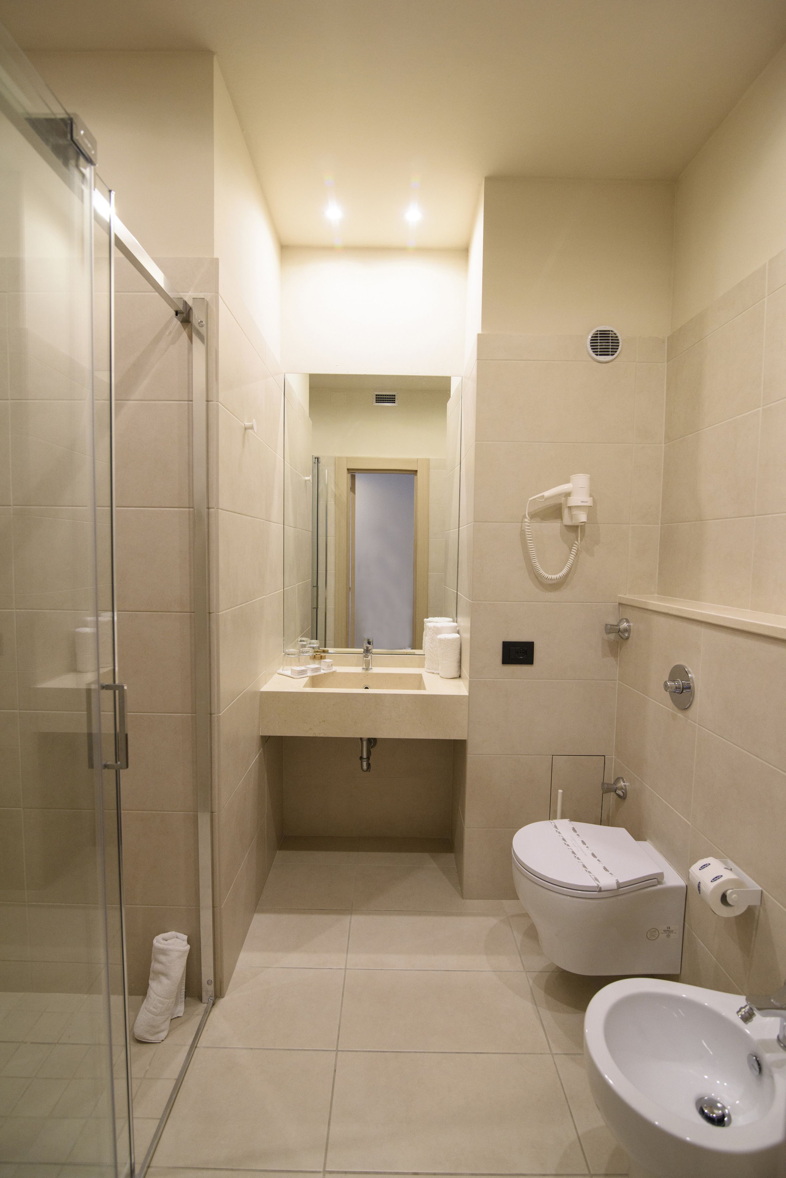 A modern bathroom with a glass shower enclosure, a toilet, a bidet, and a sink.