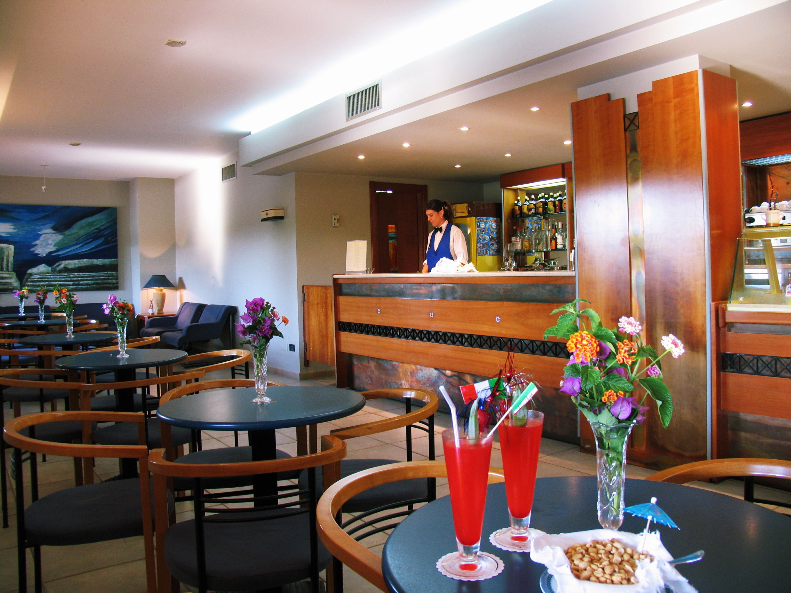 A restaurant with multiple tables and chairs, a bar area, and a reception desk.