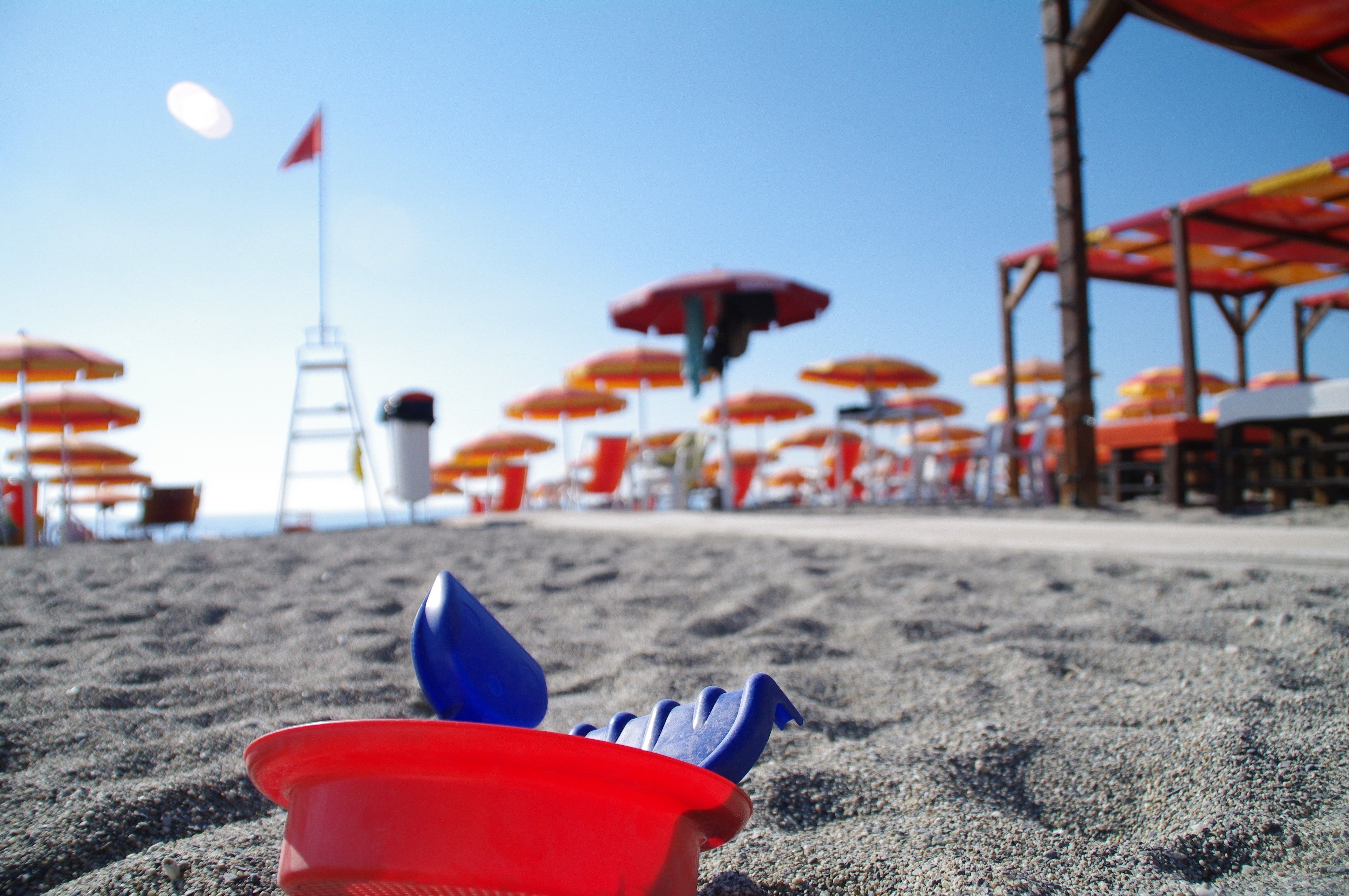 Una playa arenosa con sombrillas y una torre de salvavidas al fondo.