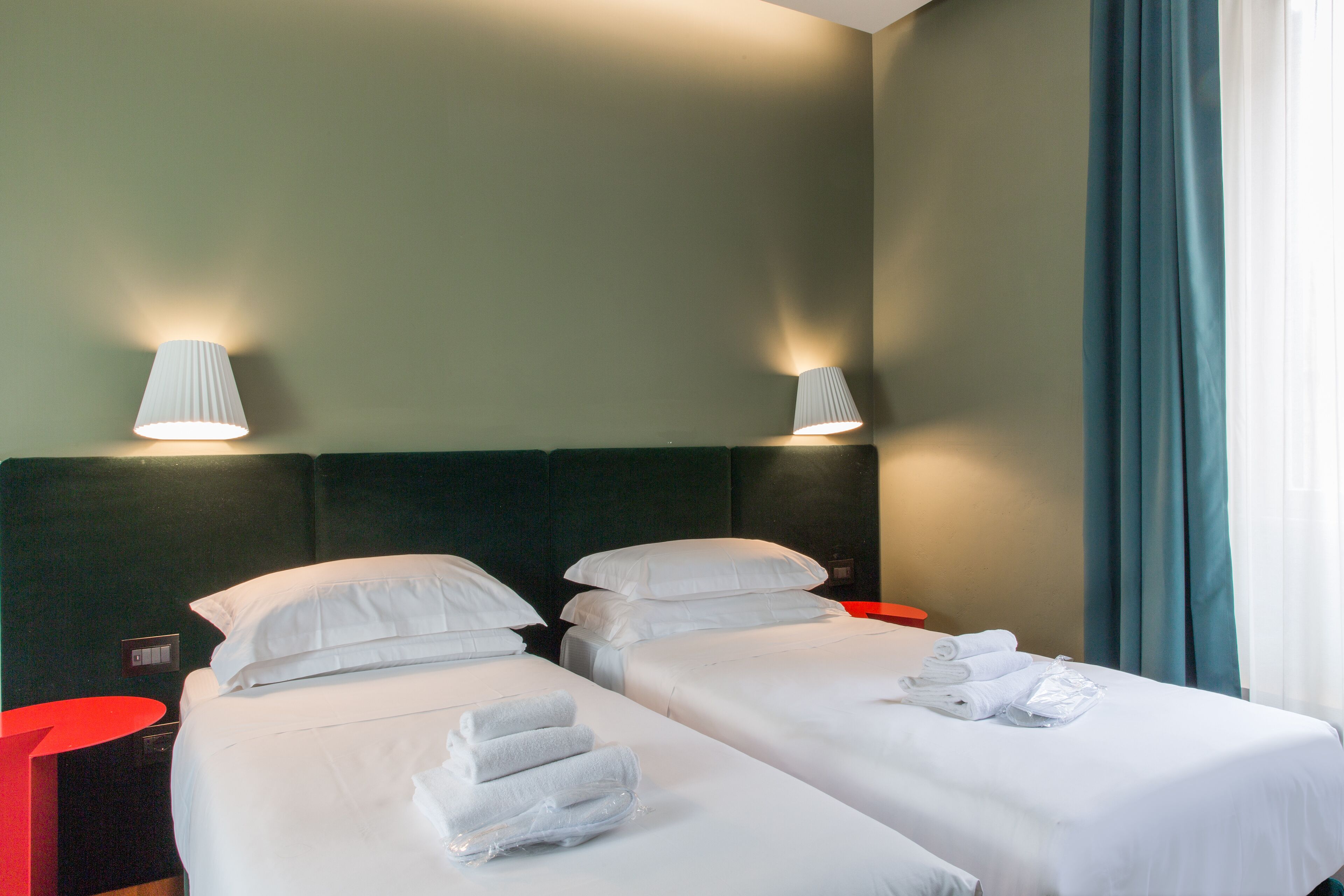 A hotel room with two beds, white linens, and two bedside lamps.