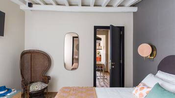 Een slaapkamer met een bed, een stoel, een spiegel en een deur naar een andere kamer.