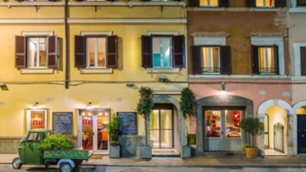 A multi-story building with balconies, a green delivery truck, and a storefront with a sign. - Condominio Monti Boutique Hotel (Rome)