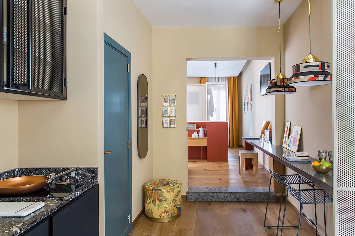 A modern kitchen with a marble countertop, a blue door, and a small stool.