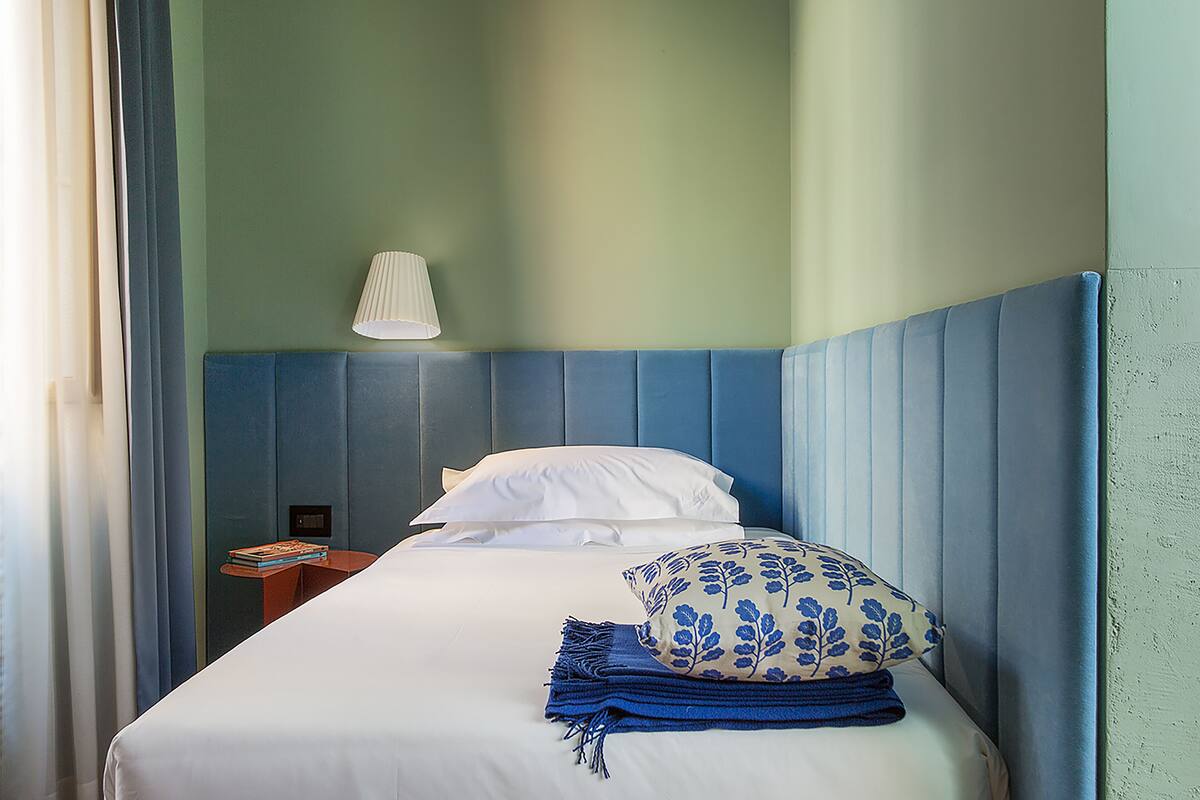 A neatly made bed with a blue headboard, white pillows, and a blue patterned pillow.