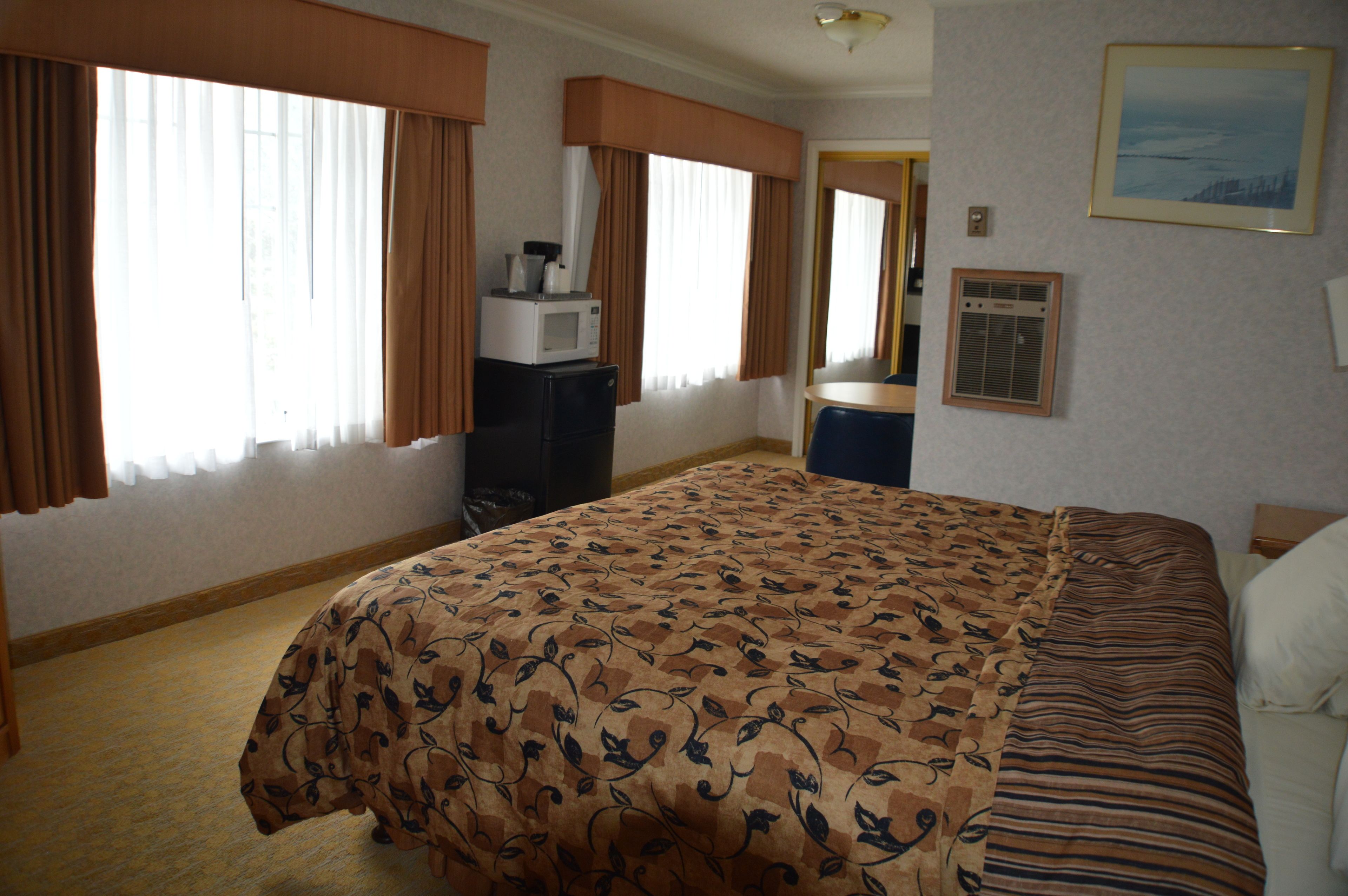 Ein Hotelzimmer mit Bett, Schreibtisch, Mikrowelle und einem gerahmten Bild an der Wand.