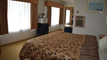 Ein Hotelzimmer mit Bett, Schreibtisch, Mikrowelle und einem gerahmten Bild an der Wand.