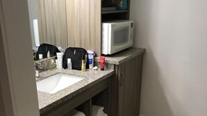 A bathroom with a granite countertop, a white sink, a microwave, and a cabinet with towels. - Castle Inn (San Francisco)