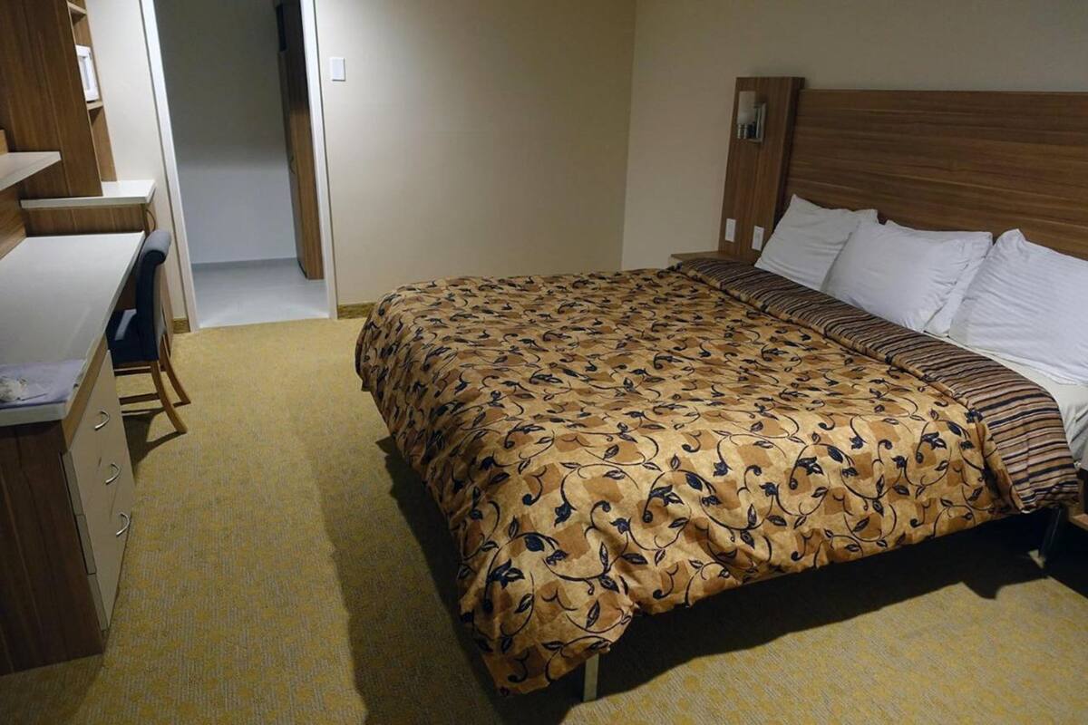A hotel room with a bed, a desk, and a chair.