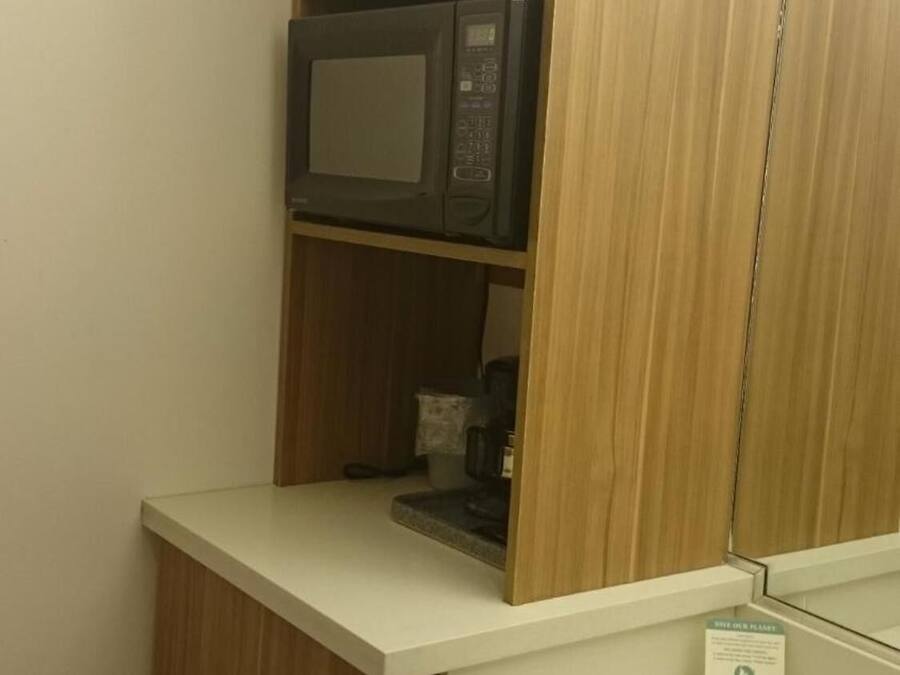 Un baño con un mueble de madera, un microondas y un lavamanos.
