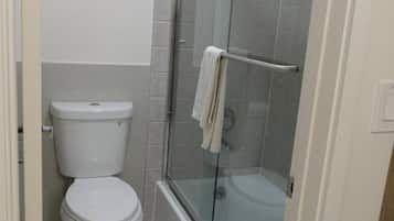 A bathroom with a toilet, a glass-enclosed shower, and a bathtub.