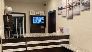 A reception area with a wooden counter, a globe, a television, and framed pictures on the wall. - Castle Inn (San Francisco)
