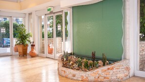 A lobby with a stone planter, potted plants, and a green wall. - Joli Park Hotel (Gallipoli)
