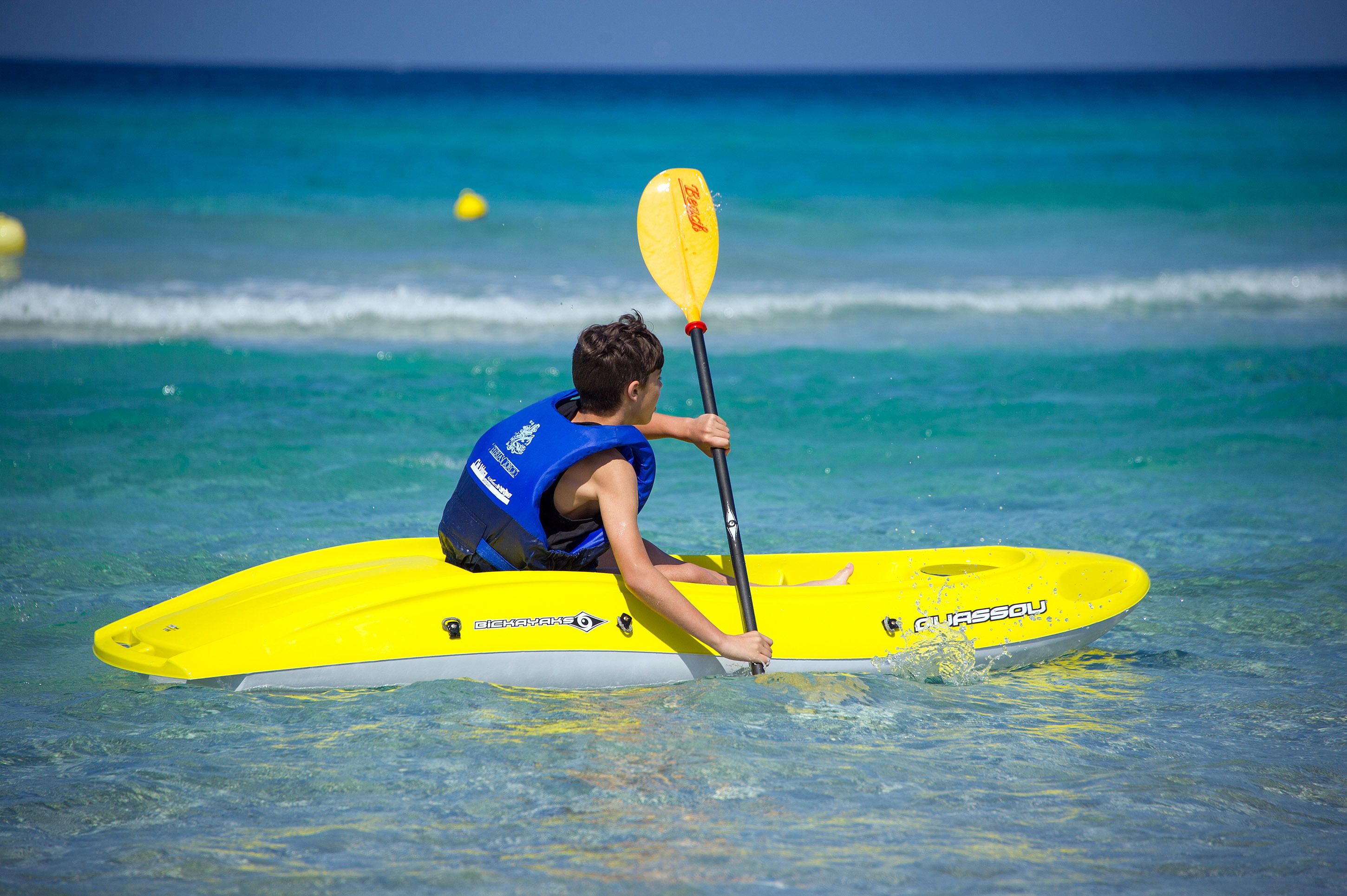 A person kayaking on a yellow board with the brand name visible.