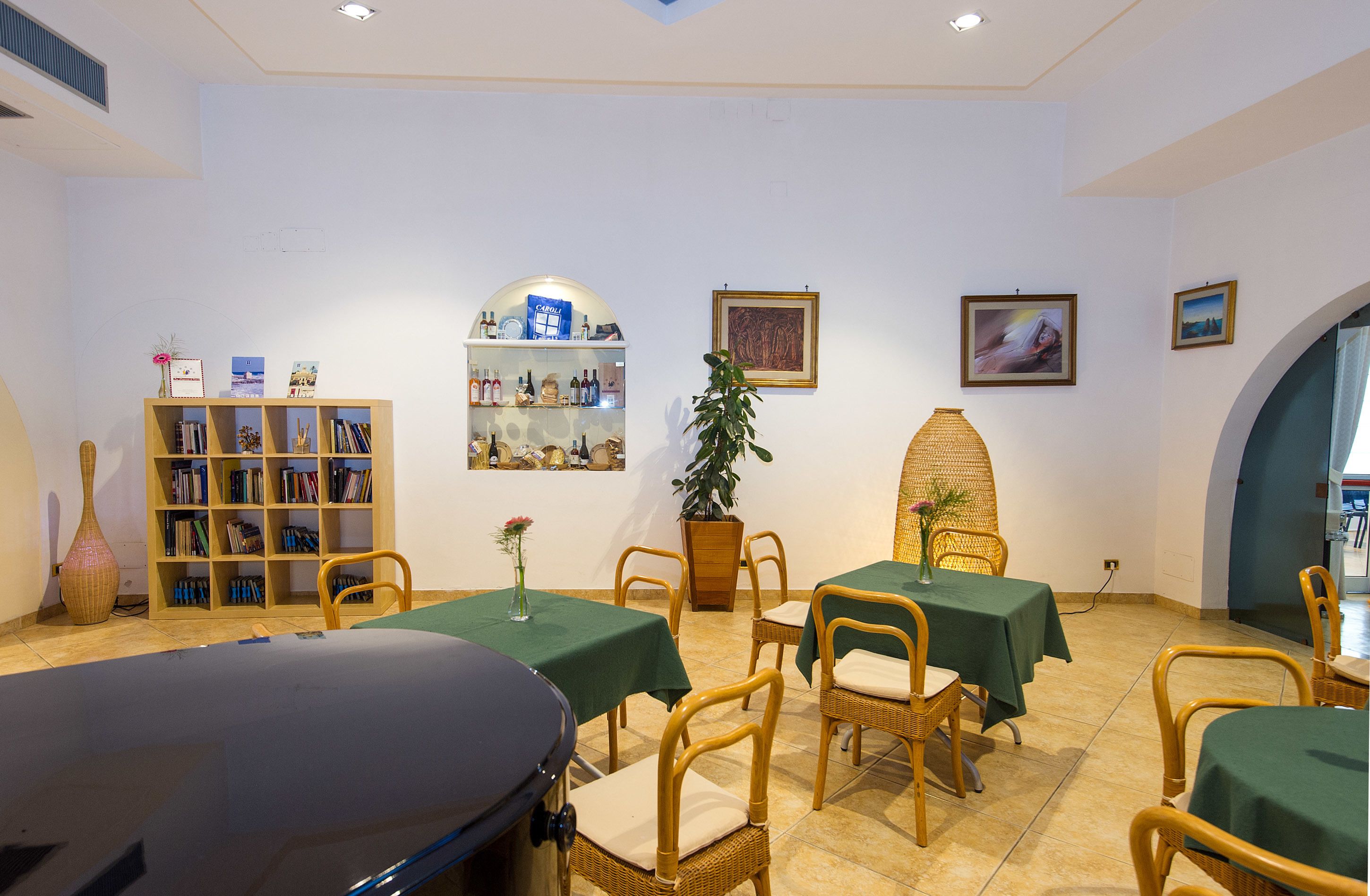 A dining area with tables and chairs, a bookshelf, and framed pictures on the walls.