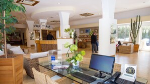 A reception area with a glass desk, wicker furniture, and a large cactus plant. - Joli Park Hotel (Gallipoli)