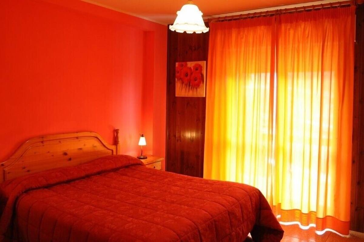 Una habitación con una cama, una mesita de noche, una lámpara y un cuadro en la pared.