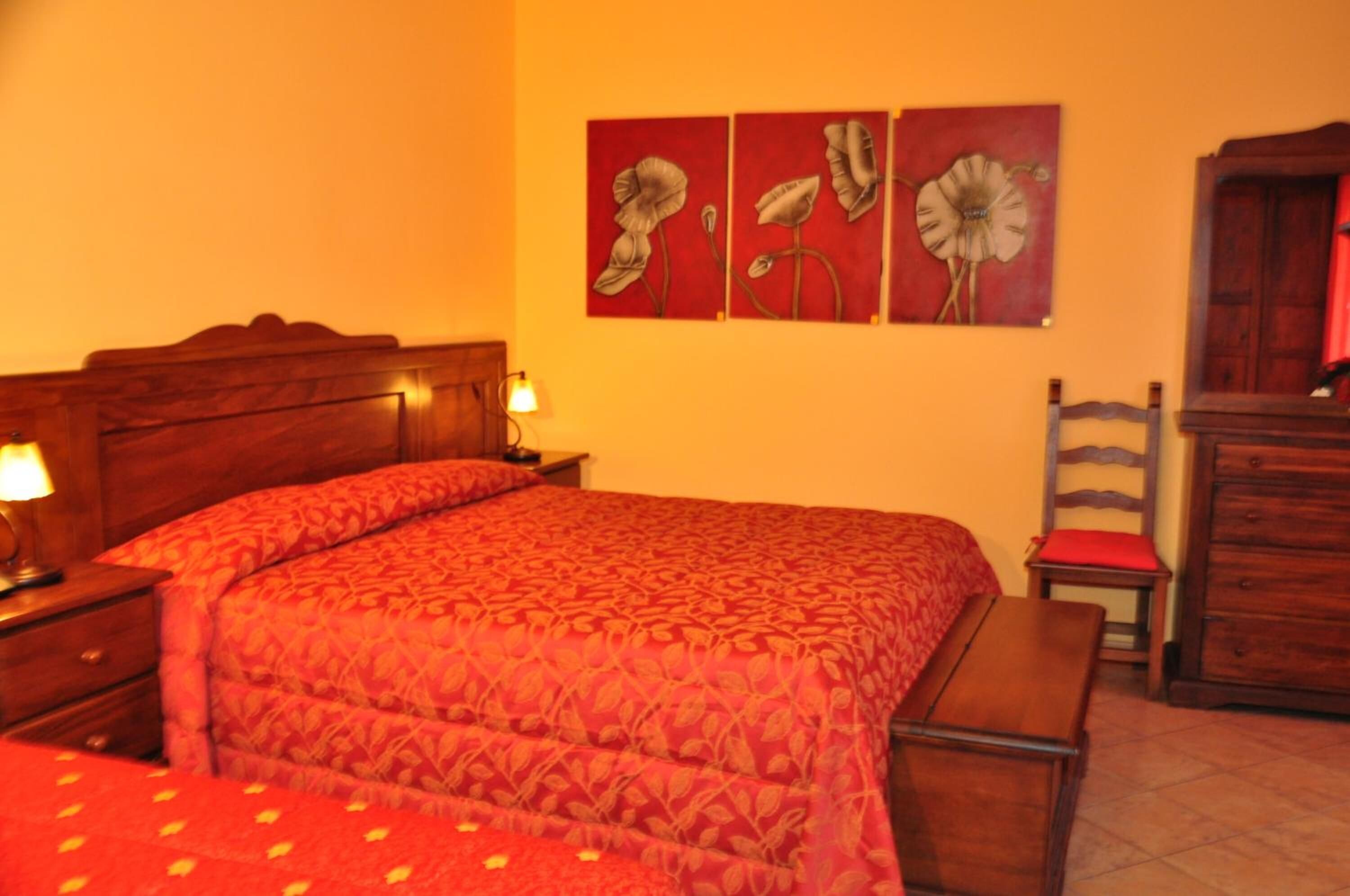 Ein Schlafzimmer mit einem hölzernen Bett, einem Nachttisch mit Lampe, einer Kommode und einem Sessel.