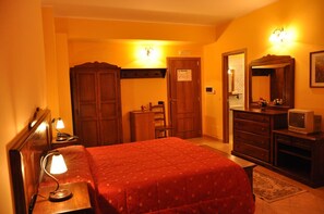 A hotel room with a bed, wooden wardrobe, dresser, and a television. - Hotel Miramonti (Santo Stefano in Aspromonte)