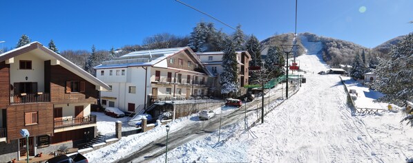 A snow-covered ski resort with multi-story buildings, a ski lift, and a chairlift. - Hotel Miramonti (Santo Stefano in Aspromonte)