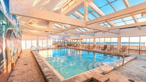 Una piscina interior con vistas despejadas al océano a través de amplios ventanales.