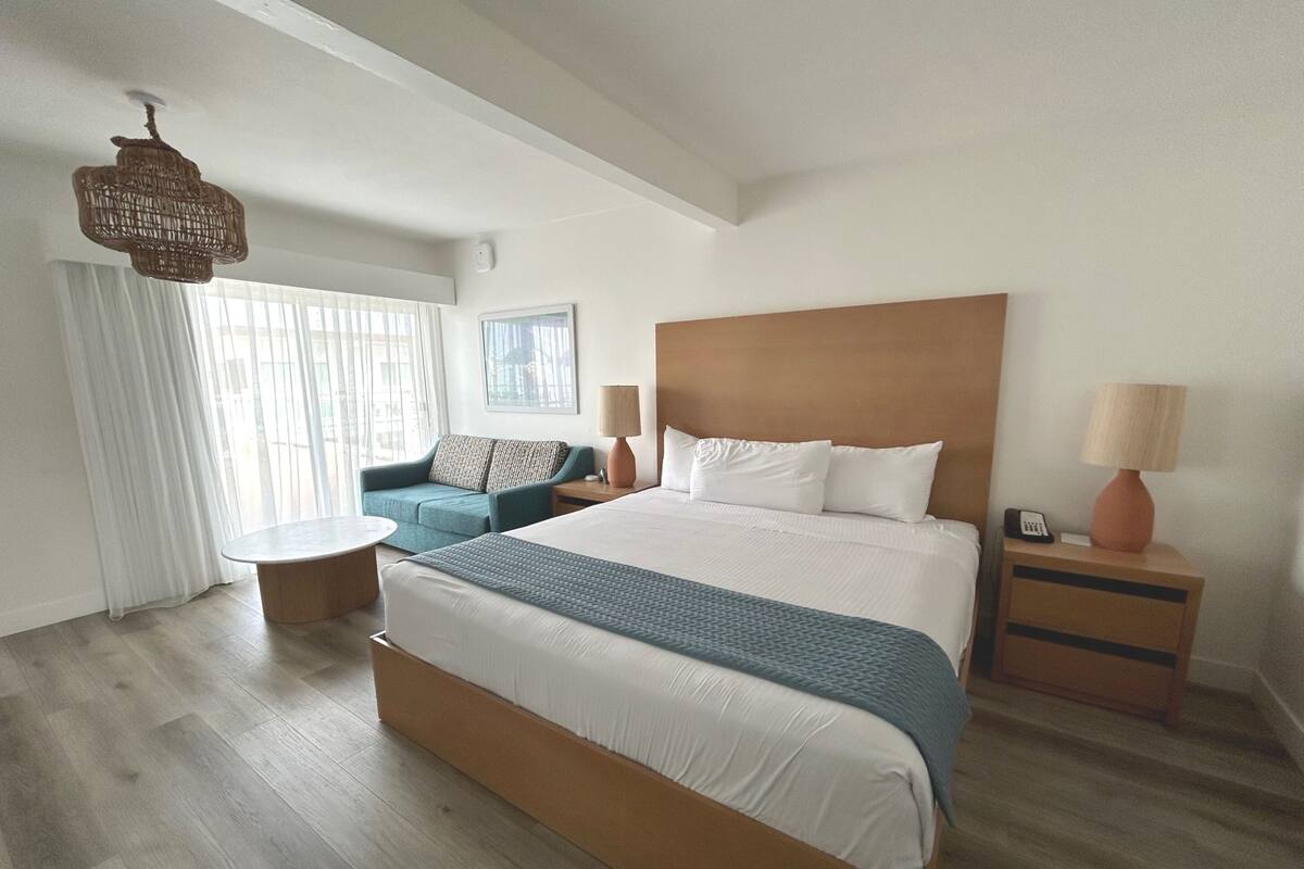 Ein modernes Hotelzimmer mit einem großen Bett, einer Couch, einem kleinen Tisch und einer Lampe.