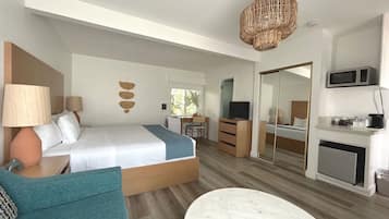 Een moderne hotelkamer met een bed, een bureau, een televisie, een magnetron en een eethoek.