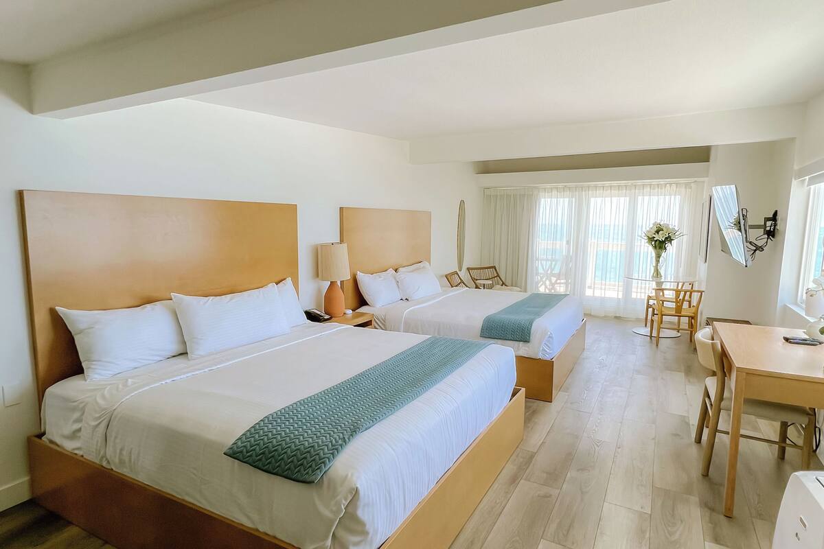 Ein Hotelzimmer mit zwei Betten, einem Schreibtisch und einem Stuhl.