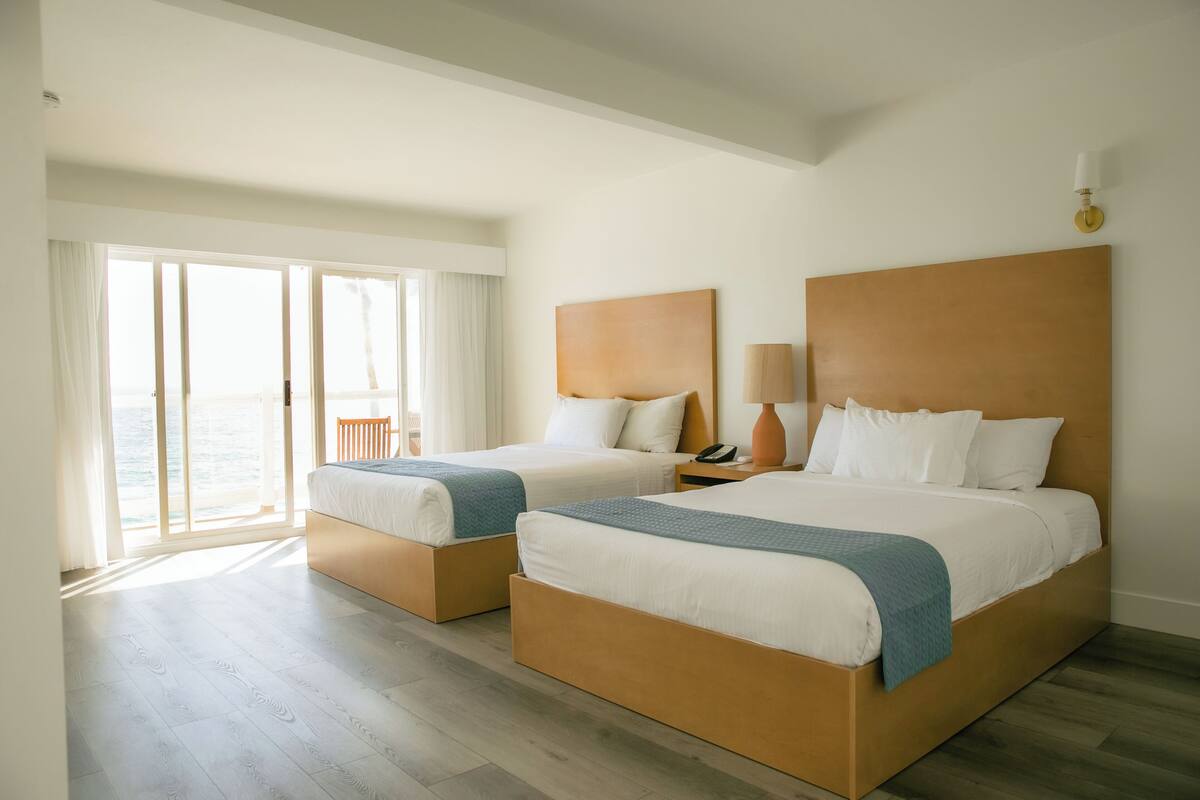 Ein Hotelzimmer mit zwei Betten, einem großen Fenster und Meerblick.