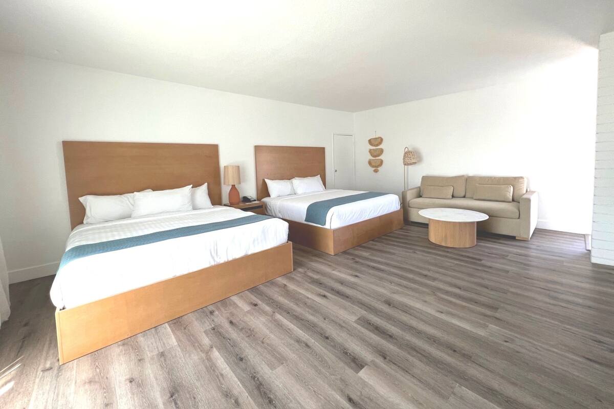 Ein Hotelzimmer mit zwei Betten, einem Schlafsofa, einem Couchtisch und einer Lampe.