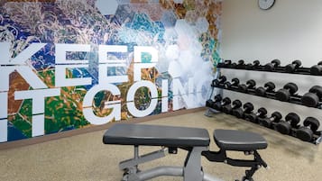 A gym with a bench, dumbbells, and a motivational wall with the text "KEEP GOING".
