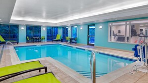 Una piscina con sillones de descanso y equipo de ejercicio.