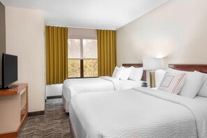 Hotellihuone, jossa on kaksi sänkyä, televisio, työpöytä ja ikkuna, jossa on verhot.