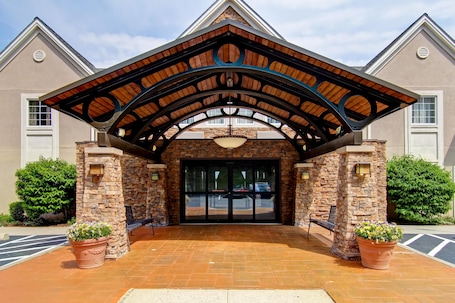 A building entrance with a stone facade, a wooden archway, and a large glass door.