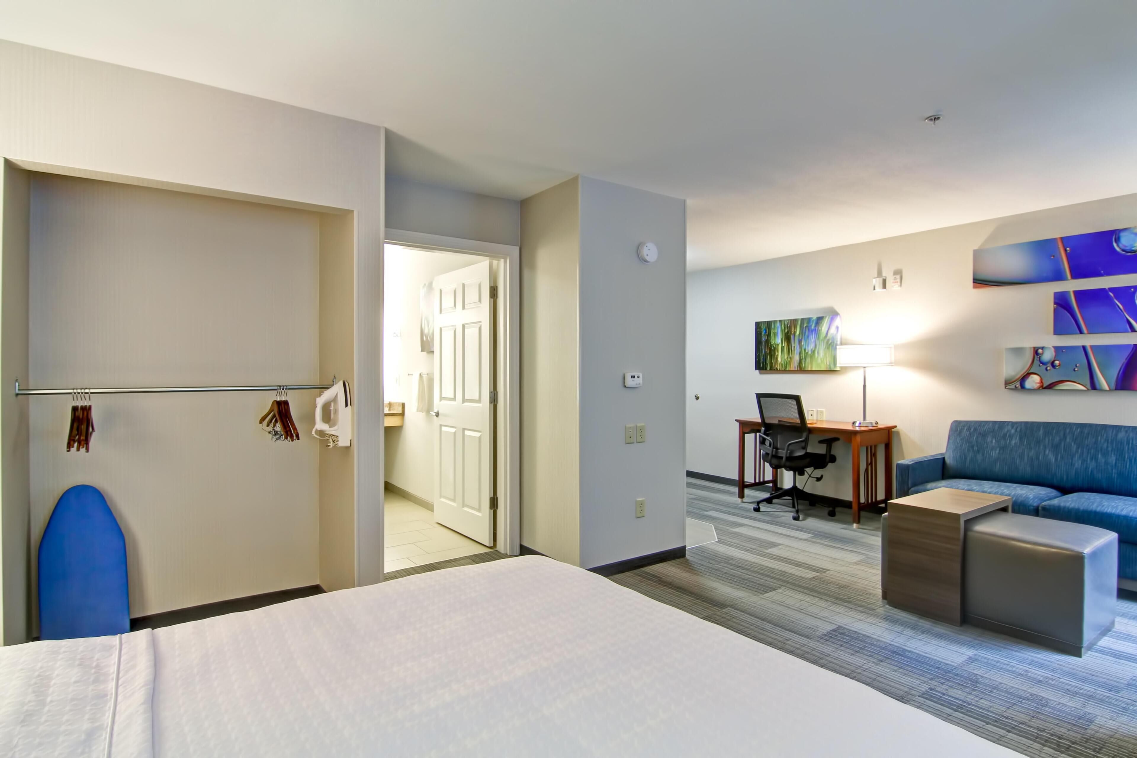 Een hotelkamer met een bed, een bureau, een stoel, een bank en een schilderij aan de muur.