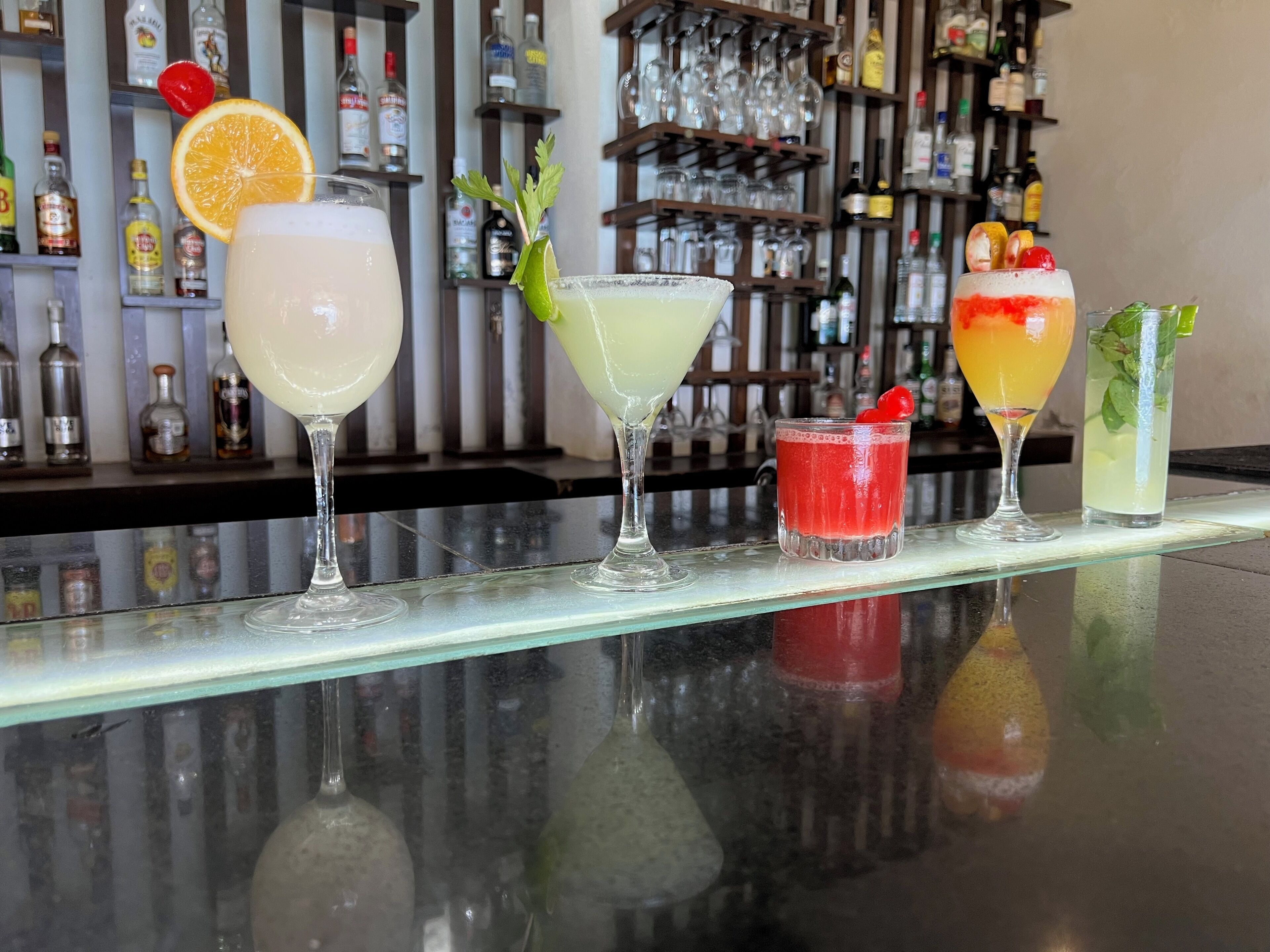 Eine Bar mit verschiedenen Cocktails, verziert mit unterschiedlichen Früchten und Kräutern.