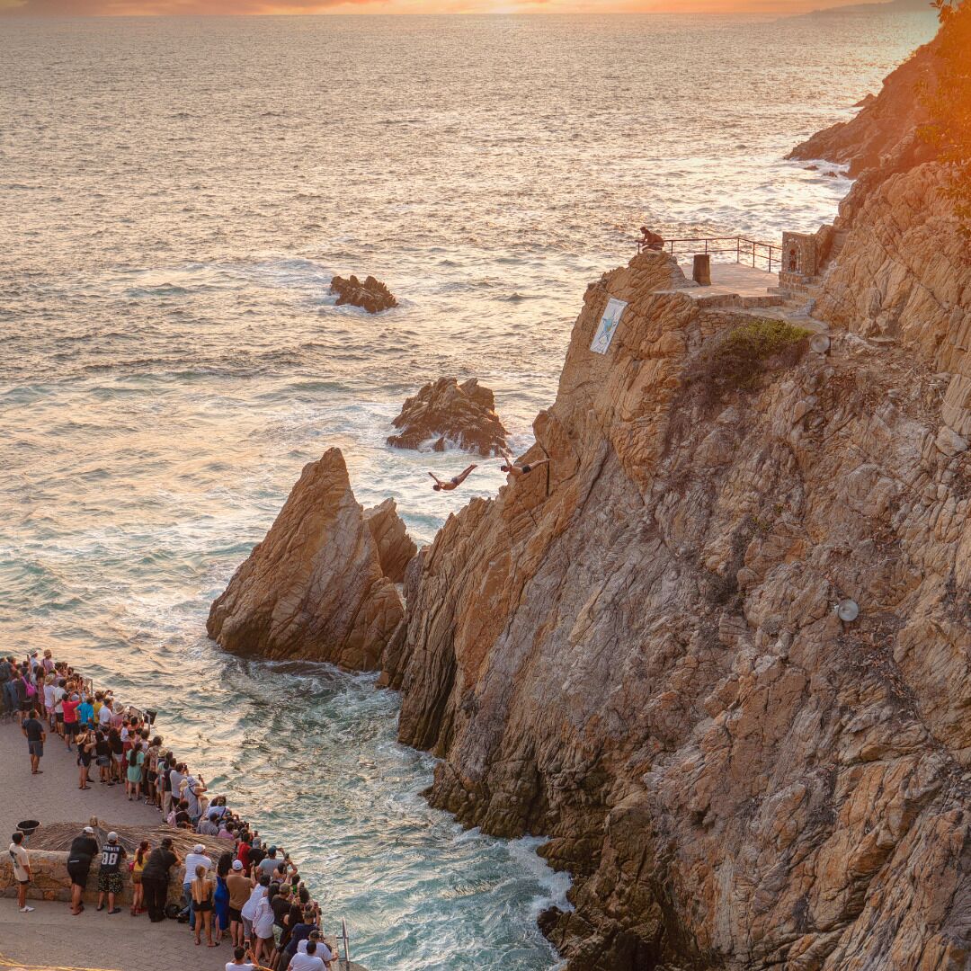 A coastal cliff with a rocky path leading to a viewing area overlooking the sea.