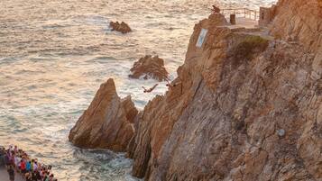 A coastal cliff with a rocky path leading to a viewing area overlooking the sea.