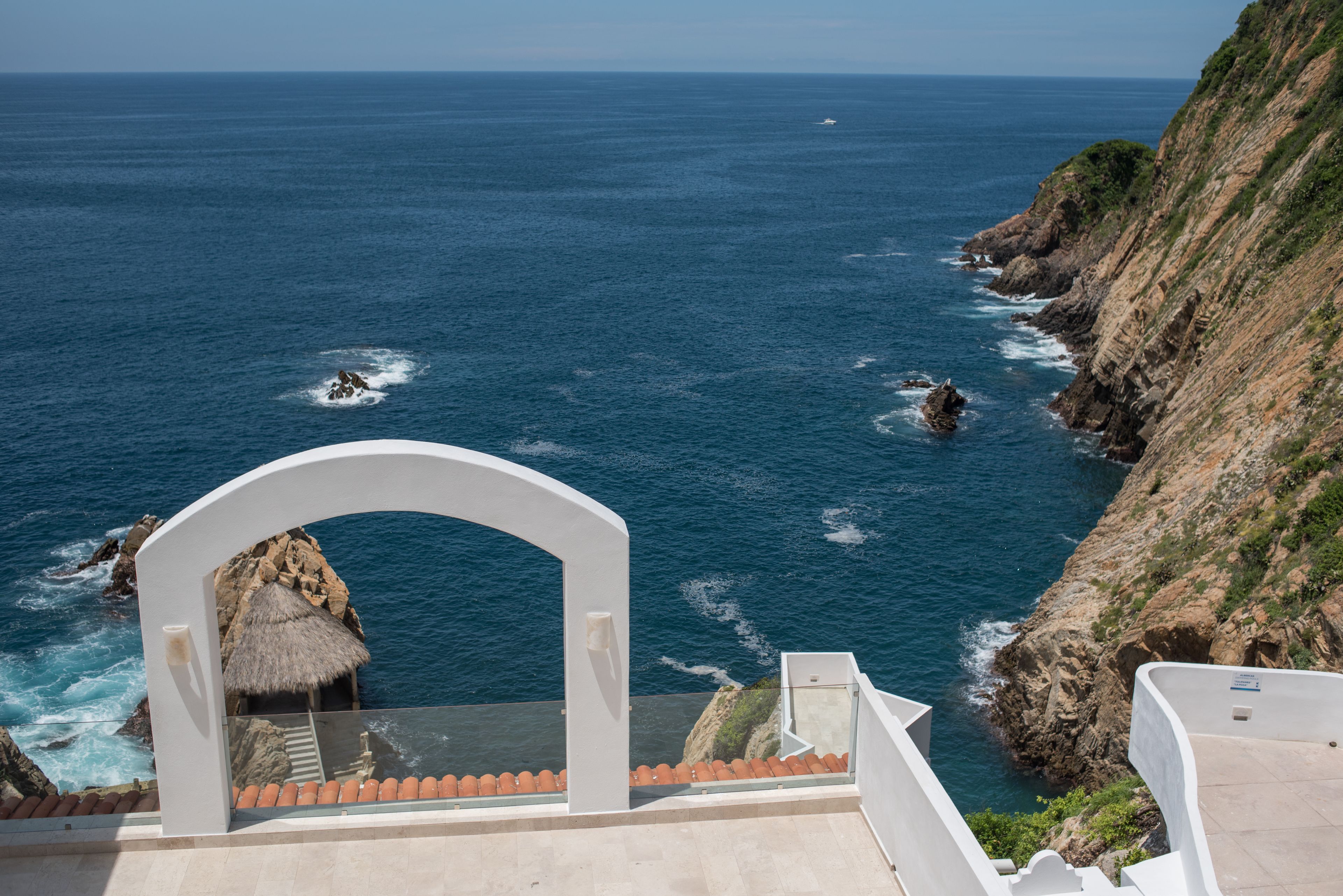 A coastal view with a white archway leading to a balcony overlooking the sea.