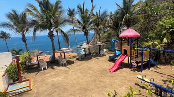 Kids can play and explore in a shaded area with a slide and climbing structures overlooking the ocean.