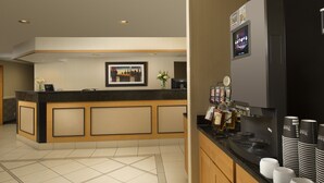 A hotel reception area with a counter, framed artwork, and a coffee machine. - Redmond Inn (Redmond)