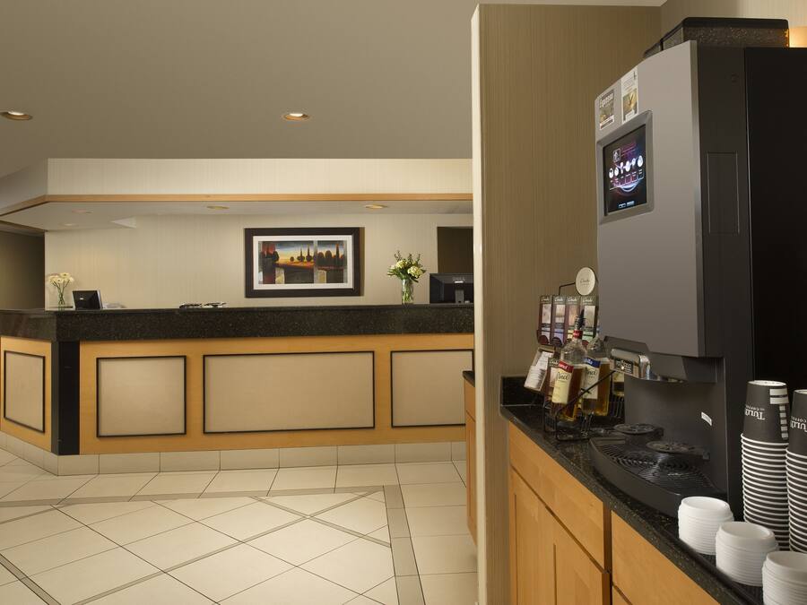 A hotel reception area with a counter, framed artwork, and a coffee machine.