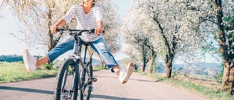 En person cykler på en belagt sti omgivet af træer med hvide blomster.