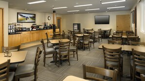 A restaurant with multiple tables and chairs, a counter with a beverage dispenser, and a television mounted on the wall. - Redmond Inn (Redmond)