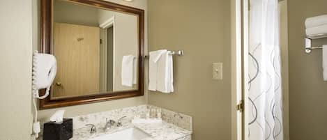 A bathroom with a marble sink, a large mirror, and a shower curtain.